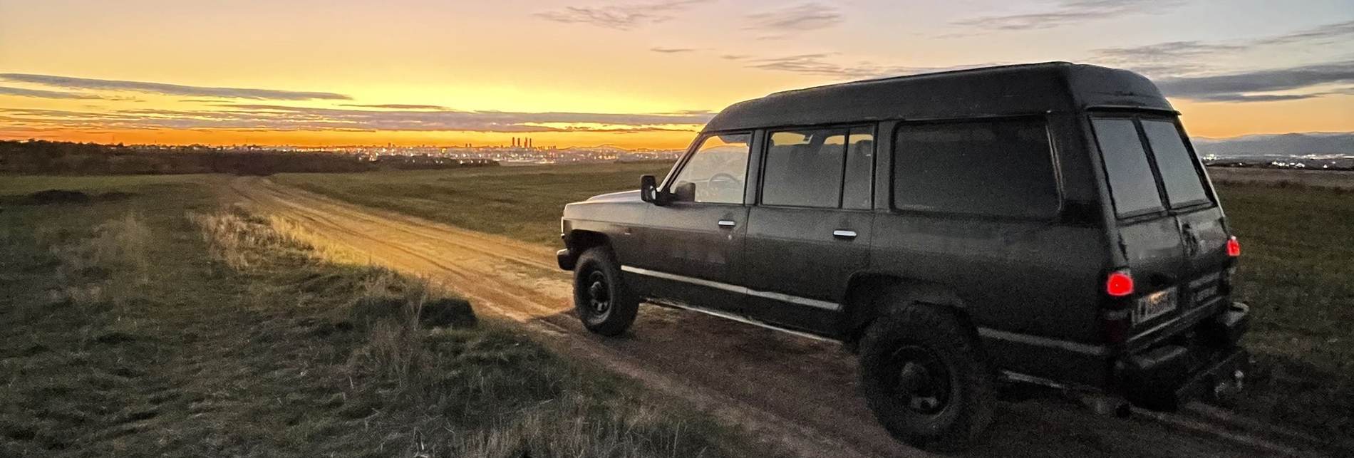 Nissan Patrol de 4x4SPAIN en una pista de tierra al amanecer, con el perfil de Madrid al fondo