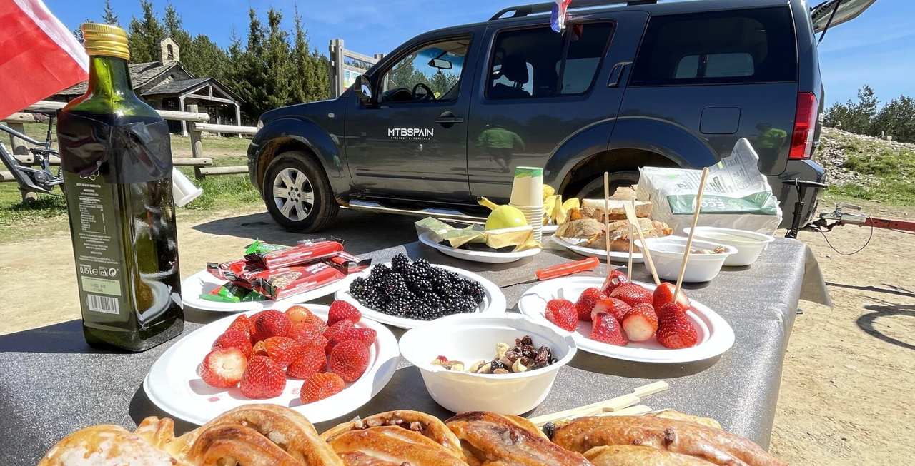 Mesa montada en plena ruta con fruta, reposteria y embutidos, junto al 4x4 de apoyo